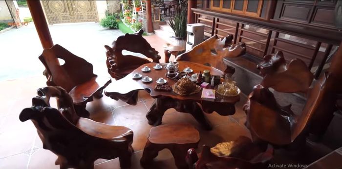 Ngoài hiên là chiếc sập gỗ gõ đỏ và bộ bàn ghế gỗ lim, được nghệ nhân tạo thành vạt ghế dựa trên lõm tự nhiên của cây cổ thụ.